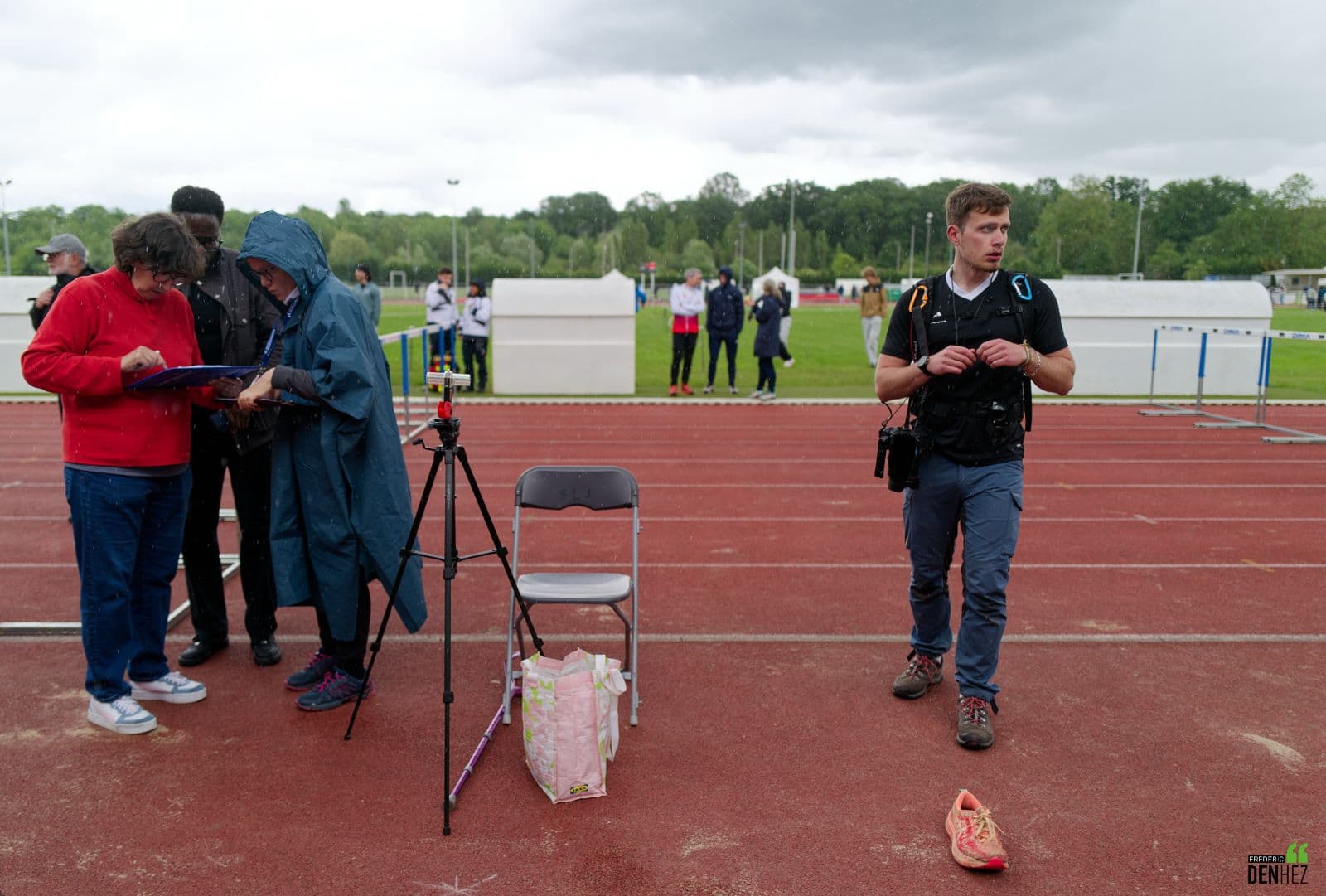 Le photographe au bord d'une piste d'athlétisme, un jour de pluie